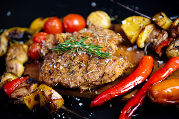 Steak on a wooden cutting board and black background sprinkled with salt and pepper.