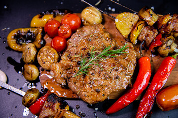 Steak on a wooden cutting board and black background sprinkled with salt and pepper.
