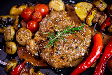 Steak on a wooden cutting board and black background sprinkled with salt and pepper.