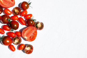 Red ripe tomatoes texture background. Different qualities of tomatoes on white linen tablecloth. Black tomato Solanum lycopersicum.
