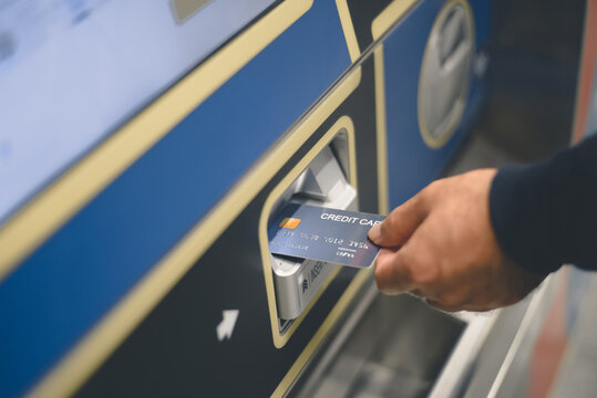 Close up of a young man hand paying using a credit card in a payment machine outdoors at subway station.