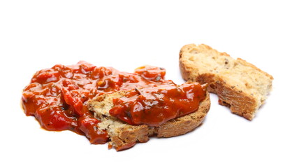Pindjur relish made from red paprika, pepper and eggplant, vegetable sauce on slice of bread isolated on white background 