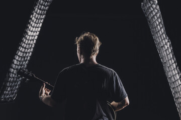 a guy in a dark T-shirt plays an electric guitar on a dark background