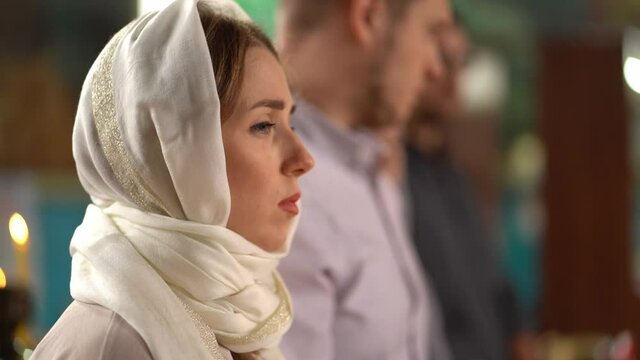 a woman in a headscarf at a church service. family religious traditions. 