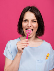 Beautiful happy young woman with tongue scraper on blank pink background