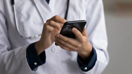 Hands of doctor in white coat using mobile phone, giving virtual online consultation, sending test...