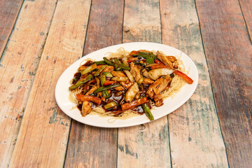 Stir-fried noodles with vegetables and chicken with lots of soy sauce cooked in a Chinese fast food restaurant