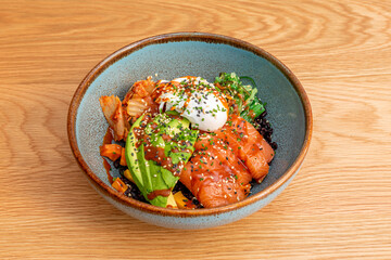 Salmon bibimbap with avocado, carrot, marinated salmon, chopped onion, wakame seaweed salad, fresh cheese in balls and seeds