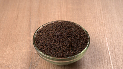 Black Tea Powder or dry dust tea powder, chai patti isolated in wooden bowl with Cardamom, Clove and Ginger.