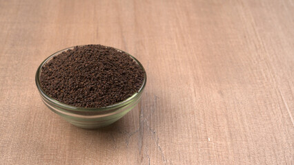 Black Tea Powder or dry dust tea powder, chai patti isolated in wooden bowl with Cardamom, Clove and Ginger.