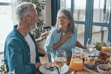 Happy senior couple communicating and smiling while having dinner together
