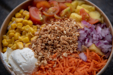 detalla de un Poke Bowl con maiz, tomate, cebolla, queso y zanahoria 