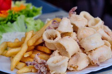 Delicious Croatian fast food - deep fried calamari and baby octopus served with French fries and fresh seasonal vegetables