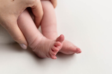 a small leg of the newborn in a white scarf. soft focus