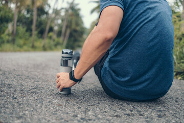 water bottle on the ground side.sport man sitting after running. Sport thirsty and resting after exercise.