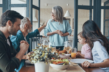 Modern multi-generation family communicating and smiling while having dinner together