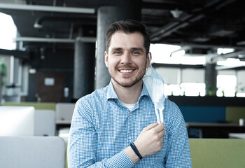 Obraz premium Businessman taking his medical protective mask off while working in the office