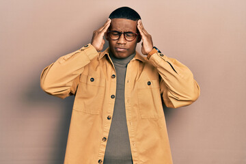 Young black man wearing casual clothes and glasses suffering from headache desperate and stressed because pain and migraine. hands on head.