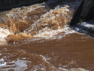Brown muddy water of Erft river in a weir in Grevenbroich in Germany