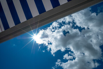 Blue awning with blue sky and clouds and star of the sun