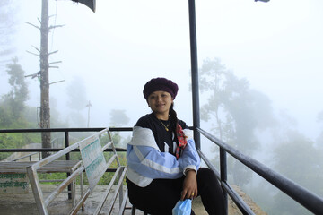 South-Asian woman sitting on a bench with a foggy background