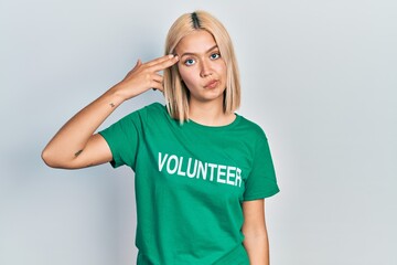 Beautiful blonde woman wearing volunteer t shirt shooting and killing oneself pointing hand and...