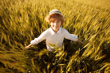 Happy boy with hat in the middle of wheat field