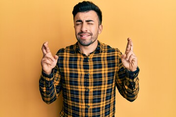 Young hispanic man wearing casual clothes gesturing finger crossed smiling with hope and eyes closed. luck and superstitious concept.