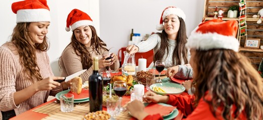 Group of young hispanic women having christmas dinner sitting on the table at home.
