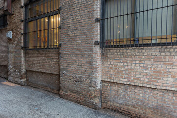 Angle view of vintage brick building and alleyway with barred windows in urban setting