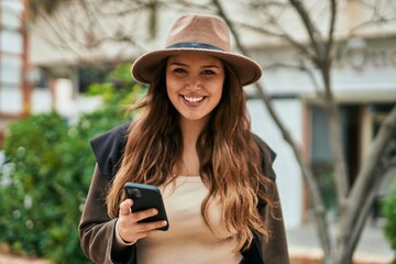 Young hispanic tourist woman using smartphone at the city.