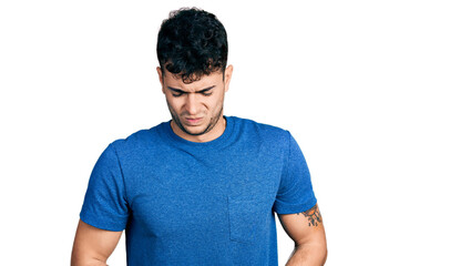 Young hispanic man wearing casual t shirt with hand on stomach because indigestion, painful illness feeling unwell. ache concept.