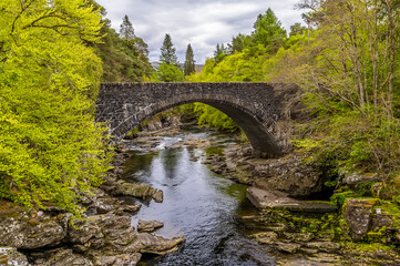 Fototapeta na wymiar A view towards the road bridge over the falls at Invermoriston, Scotland on a summers day