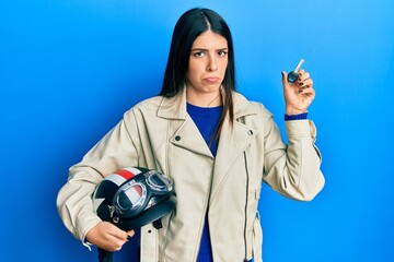 Young hispanic woman holding motorcycle helmet and key depressed and worry for distress, crying angry and afraid. sad expression.