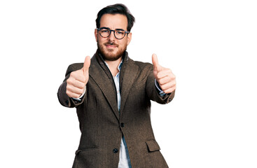 Young hispanic man wearing business jacket and glasses approving doing positive gesture with hand, thumbs up smiling and happy for success. winner gesture.