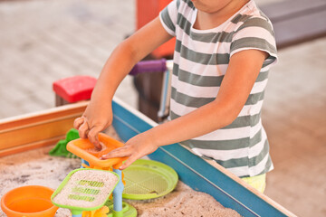 Little kid girl playing at the outdoor playground with sand and toys