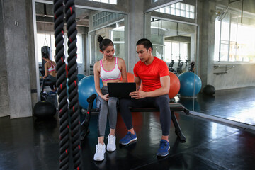 Women are discussing fitness with trainers. Young female talking during workout in gym. Young couple talking during workout in fitness center.