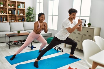 Young latin sporty couple smiling happy training at home.