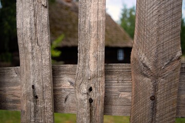 Rails of a rural wooden fence with a hut in the background.