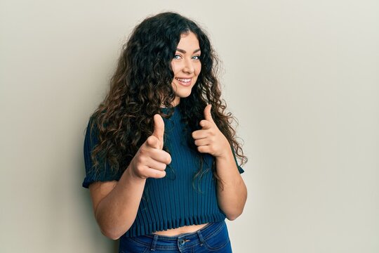 Young brunette woman with curly hair wearing casual clothes pointing fingers to camera with happy and funny face. good energy and vibes.
