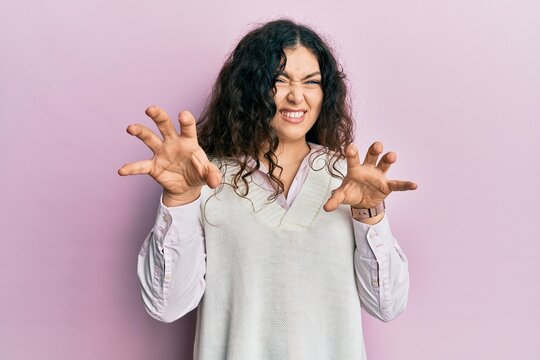Young brunette woman with curly hair wearing casual clothes smiling funny doing claw gesture as cat, aggressive and sexy expression