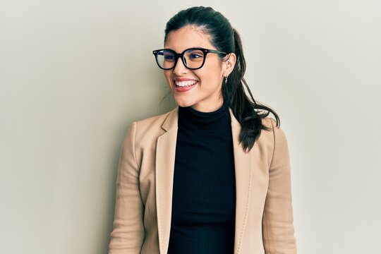 Young hispanic woman wearing business style and glasses looking away to side with smile on face, natural expression. laughing confident.
