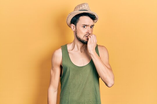 Young hispanic man wearing summer hat looking stressed and nervous with hands on mouth biting nails. anxiety problem.