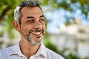 Middle age grey-haired man smiling happy standing at the city.