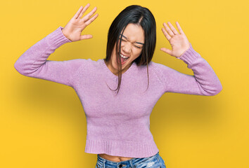 Young hispanic girl wearing casual clothes celebrating mad and crazy for success with arms raised...