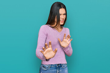 Young hispanic girl wearing casual clothes disgusted expression, displeased and fearful doing disgust face because aversion reaction. with hands raised