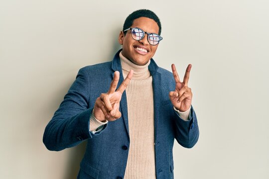 Young handsome hispanic man wearing elegant clothes and glasses smiling looking to the camera showing fingers doing victory sign. number two.