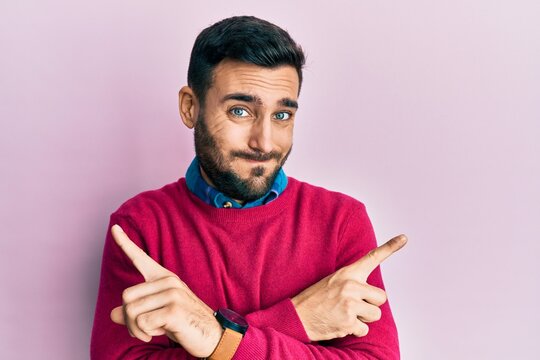 Young hispanic man wearing casual clothes pointing to both sides with fingers, different direction disagree