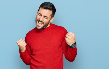 Young hispanic man wearing casual clothes very happy and excited doing winner gesture with arms...