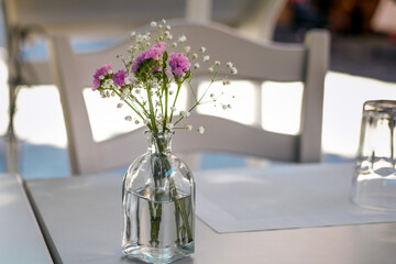 Field flowers in glass vase as dinner table decoration in street restaurant